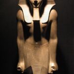Statue of Pharaoh Thutmose III wearing the Nemes headdress and Uraeus, depicted in a pose of worship or offering.