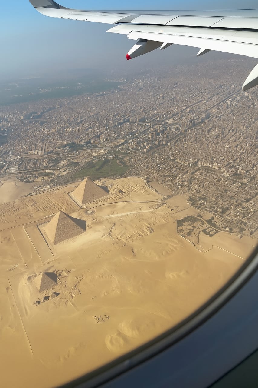 Aerial view of the Giza Necropolis showing the three Great Pyramids from an airplane window.