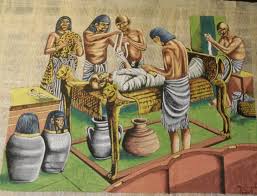 Depiction of the ancient Egyptian mummification process, with embalmers preparing a body and canopic jars for organ storage.
