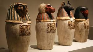 Ancient Egyptian Canopic Jars with lids representing the Four Sons of Horus, used to store and protect organs during mummification.